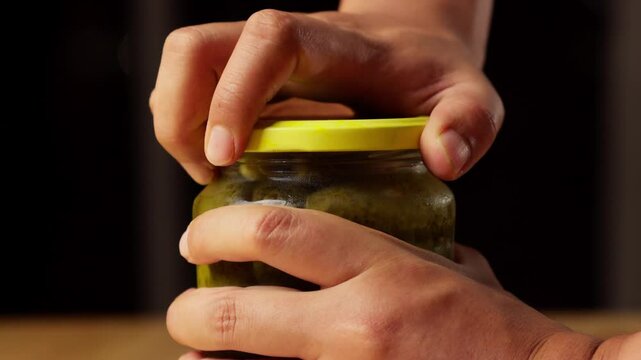 person opening cucumber pickle jar