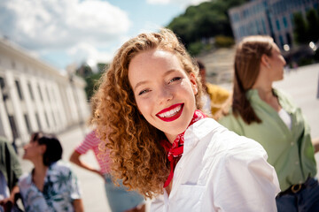 Young woman enjoying a sunny day outdoors with friends in a vibrant city setting during summer
