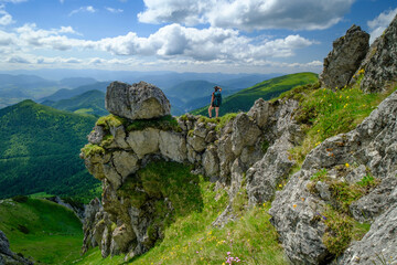 A woman with a backpack stands on a cliff in the Mala Fatra Mountains in Slovakia
