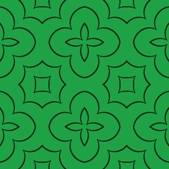 A repeating geometric pattern with floral elements is arranged in a symmetric manner on a green background. 