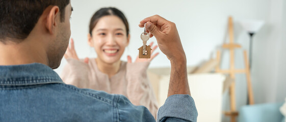 Fototapeta premium Moving house, relocation. Husband show key new condominium or house for husband, inside the room was a cardboard box containing personal belongings and furniture. move in the apartment.