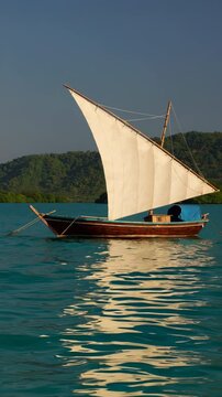 Traditional dhow sailing boat reflecting on calm turquoise water