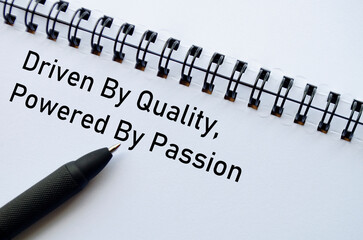 Driven By Quality Powered By Passion on notebook with pen on wooden surface