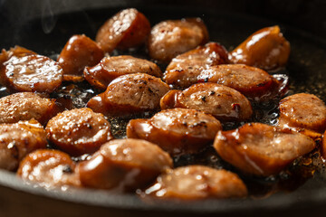 A pan of sizzling hot dogs with a lot of seasoning