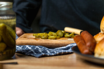 A person is cutting up pickles into thin slice on a wooden cutting board