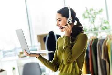 Starting a small business professional woman working remotely with a laptop and headset in a...