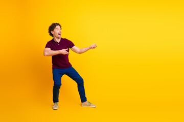 Cheerful young man in casual attire gesturing with excitement on a bright yellow background, showcasing vibrant energy.
