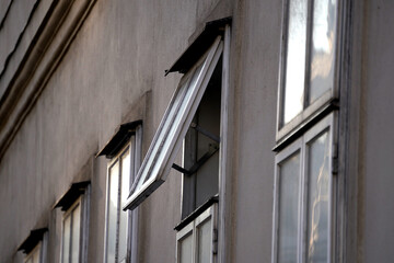 Close-up of open industrial window in an aging concrete facade with worn paint and muted...