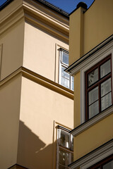 Minimalist yellow architecture with sharp shadows and classic windows. Clean stucco facade in sunlight creates strong geometric contrast for urban and design backgrounds.

