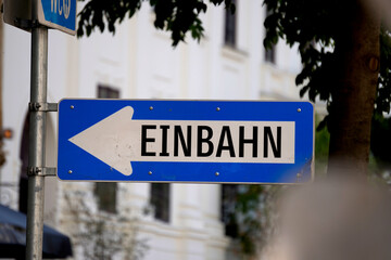 Close-up of blue German one-way street sign with bold arrow. Urban signage guides traffic...