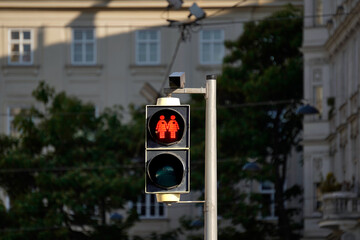 Urban traffic light displays red lesbian couple icon. Equality symbol in modern city crosswalk. Inclusive infrastructure promotes diversity. Symbolic signal supports LGBTQ rights.

