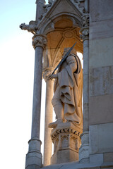 Medieval stone statue of warrior with sword. Carved figure in gothic niche under soft sunlight....