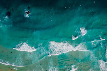 Obraz na płótnie Canvas Top down view of blue ocean with crashing waves, drone shot