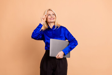 Professional mature woman wearing elegant blue shirt holding a laptop and smiling confidently...