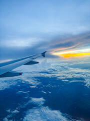 A serene aerial perspective from an airplane window, showcasing the aircraft wing gliding above a...
