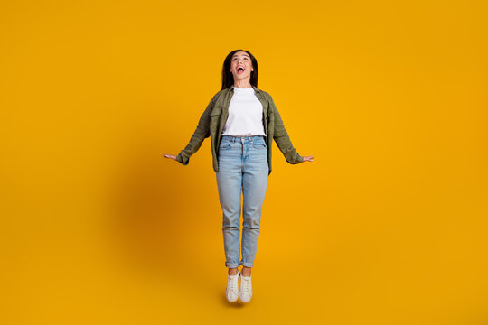 Cheerful young woman wearing casual fashion poses joyfully against a yellow background