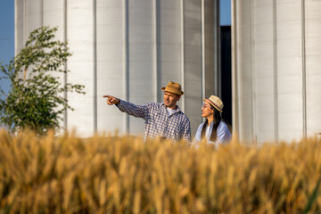 Two Silo Workers Standing in Wheat Field Looking At Something In The Distance