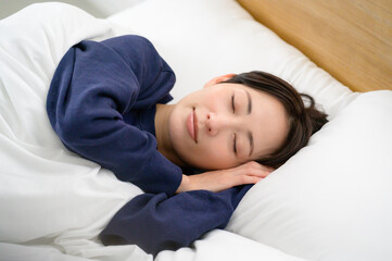 安らかな寝顔を見せる女性が布団の中で優しく眠る穏やかなひととき