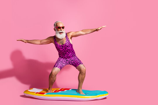 Photo of cheerful crazy cool grandfather wear swimsuit resort surfing wave isolated on pink color background