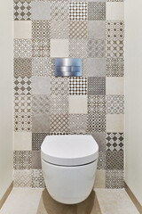 Modern and stylish bathroom design with wall-mounted white toilet set against vibrant patchwork of...
