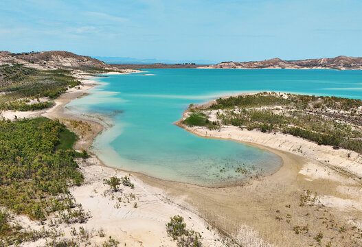 Aerial view of Embalse de La Pedrera reservoir landscape, with striking turquoise waters, curving white-sand shores, and desert-like hills in distance. Costa Blanca. Province of Alicante. Spain