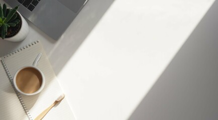 Morning desk scene with coffee, notebook, and laptop under sunlight