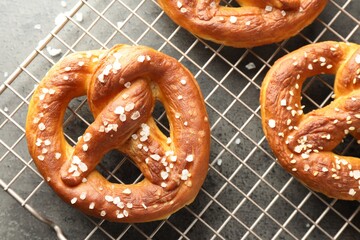 Tasty pretzels with salt on grey table, top view