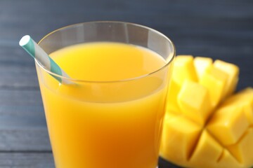 Tasty mango juice in glass and fresh fruit on table, closeup