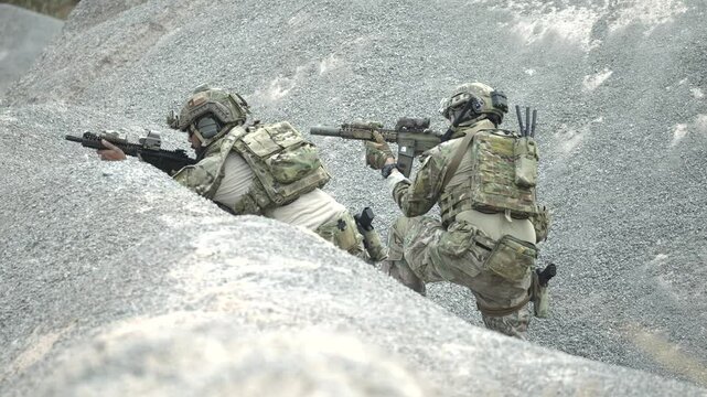 Armed special forces soldiers in camouflage gear aim rifles during a live tactical operation in jungle terrain, showcasing teamwork, readiness, and mission focus in action.