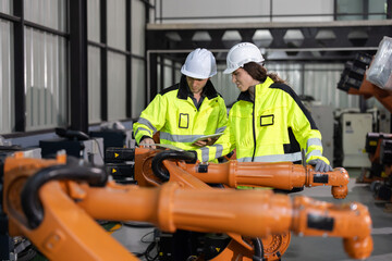 Two engineers work  in a  robotic arm manufacturing facility