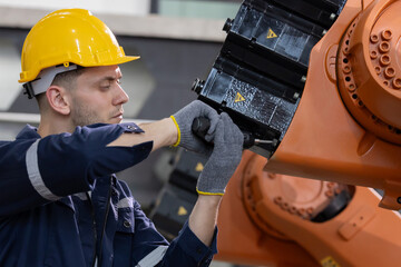 Technician repairs robotic arm in manufacturing facility