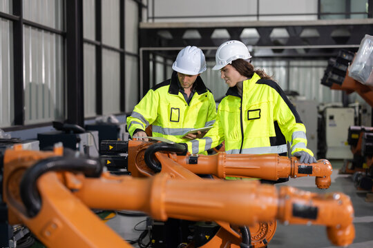 Two engineers work  in a  robotic arm manufacturing facility