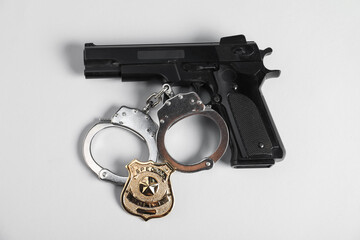 Police badge, gun and handcuffs on white background, above view