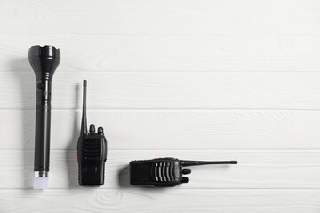 Police equipment. Flashlight and walkie talkies on white wooden table, flat lay. Space for text