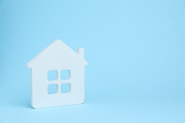 One white house model on light blue background, space for text