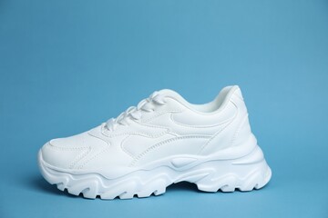 One stylish white sneaker on light blue background