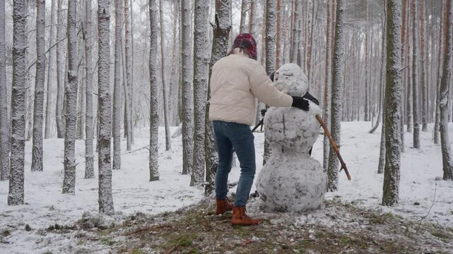 Two brothers work together on their snowman, then step back to review and assess their progress. This creative process involves evaluating their work from a distance before making adjustments.