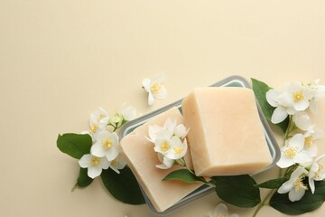 Soap bars and jasmine flowers on beige background, flat lay. Space for text