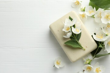 Soap bar and jasmine flowers on white wooden table, flat lay. Space for text