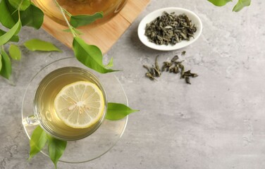Refreshing green tea with lemon and leaves on light table, flat lay. Space for text