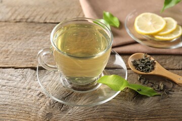 Refreshing green tea with lemon and leaves on wooden table, closeup