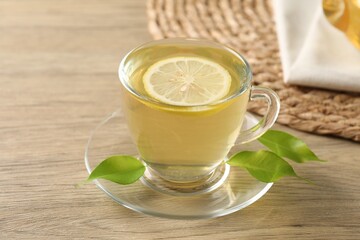 Refreshing green tea with lemon and leaves on wooden table, closeup