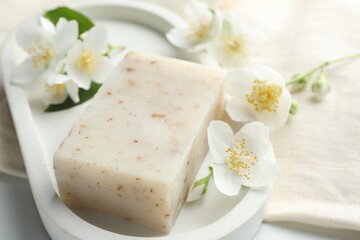 Soap bar and jasmine flowers on white table, closeup