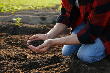 Man holding pile of soil in field, closeup