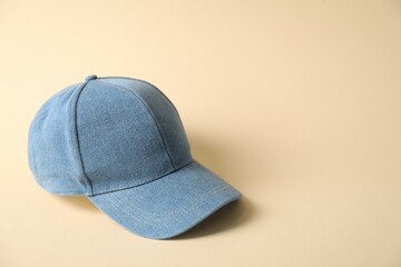 Denim baseball hat on beige background, space for text