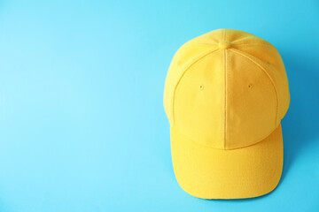 Yellow baseball hat on light blue background, above view. Space for text