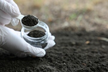 Scientist taking soil sample for research outdoors, closeup. Space for text