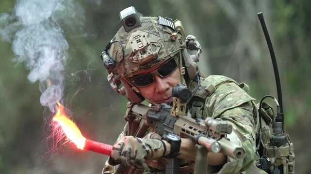 A special forces soldier holds a burning red signal flare during a jungle operation A dramatic close up concept for survival emergency signals and rescue missions