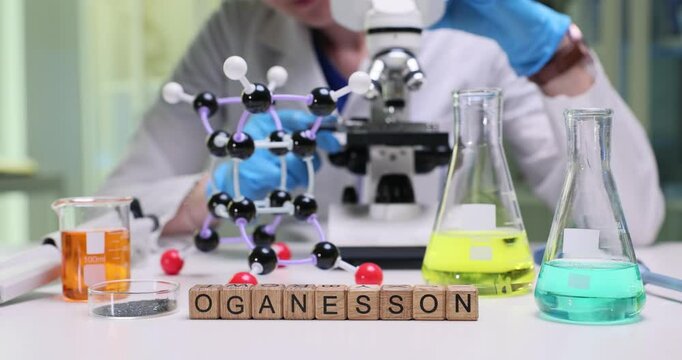 A scientist studies molecular models of Oganesson in a lab, surrounded by different chemical solutions