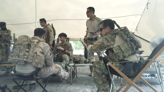 Special forces personnel attend a briefing under a tent possibly in urban reviewing equipment and strategy before an operation